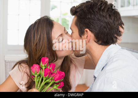 Couple d'amour avec des fleurs à la main à la maison Banque D'Images