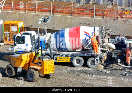 Tombereau et livraison de ciment en béton mélangé prêt à l'emploi vue du camion depuis le dessus les travailleurs portent des vêtements haute visibilité sur le chantier de construction Londres Royaume-Uni Banque D'Images