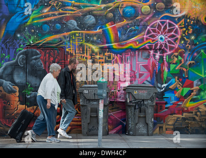 L'homme et la femme à pied sur un trottoir passé Street Art alors que Suitcase Downtown, San Diego, California USA Banque D'Images