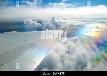 Aile d'avion volant au-dessus des nuages dans le ciel et avec une vue sur l'océan en arrière-plan Banque D'Images