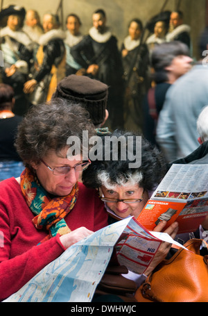 Les visiteurs de l'art galeries du Rijksmuseum à Amsterdam assis en face de grands tableaux Banque D'Images