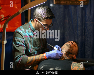 Un tatoueur travaille sur un cou de l'homme au New York City Tattoo Convention au Hammerstein Ballroom à Midtown Manhattan, NY Banque D'Images