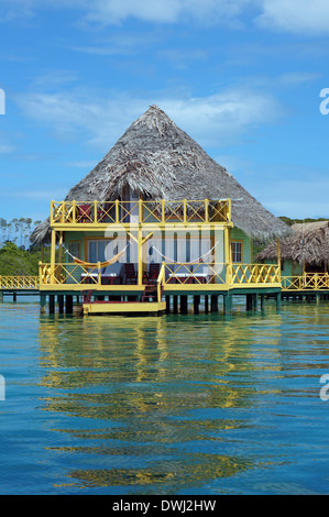 Bungalow tropical sur pilotis sur l'eau avec toit de chaume de palmier, Bocas del Toro, la mer des Caraïbes, l'Amérique centrale, le Panama Banque D'Images