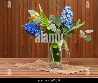 Bouquet de tulipes et jacinthes en vase en verre sur fond de bois. Banque D'Images