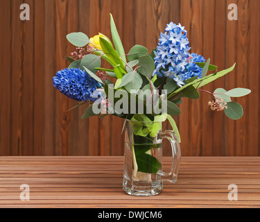 Bouquet de tulipes et jacinthes en vase en verre sur fond de bois. Banque D'Images