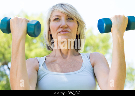 Woman lifting dumbbells in park Banque D'Images