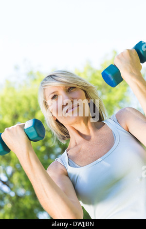 Woman lifting dumbbells in park Banque D'Images