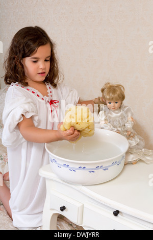 Adorable petite fille victorienne laver sa poupée vintage Banque D'Images