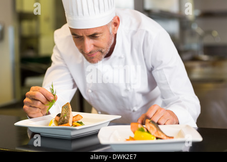 Concentrés male chef garniture food in kitchen Banque D'Images