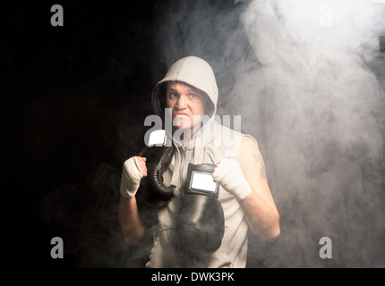 Dire à la jeune boxeur psyching lui-même avant un match de plier son poing et grondant dans une atmosphère de fumée sombre Banque D'Images