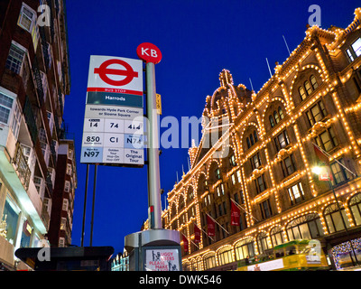 Harrods de nuit avec son propre arrêt de bus et passant tour bus Knightsbridge London UK Banque D'Images