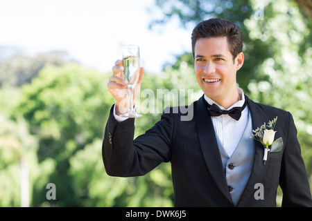 Groom toasting champagne flute in garden Banque D'Images