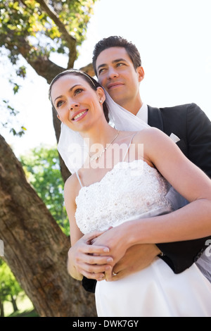 Thoughtful newly wed couple standing in garden Banque D'Images