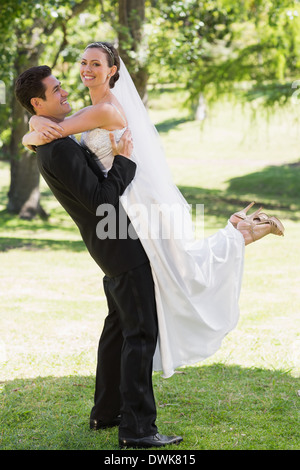 Vue de côté marié mariée de levage dans jardin Banque D'Images