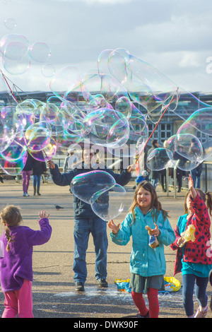 Artiste de rue bulles coups pour les enfants de London South Bank. Enfants jouant avec des bulles Banque D'Images