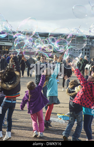 Artiste de rue bulles coups pour les enfants de London South Bank. Enfants jouant avec des bulles Banque D'Images