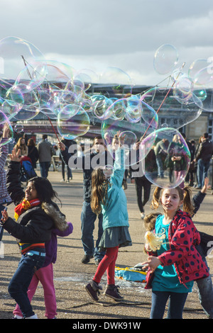 Artiste de rue bulles coups pour les enfants de London South Bank. Enfants jouant avec des bulles Banque D'Images