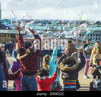 Artiste de rue bulles coups pour les enfants de London South Bank. Enfants jouant avec des bulles Banque D'Images