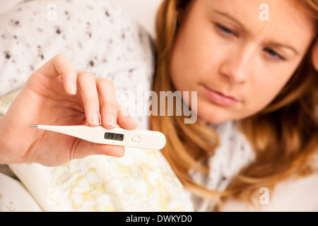 Woman feaver avec digital a termomether girl avec la grippe resting in bed Banque D'Images