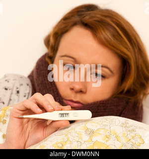 Woman with digital de la fièvre de la grippe a termomether avec girl resting in bed Banque D'Images