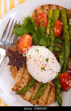 Œuf poché sur pain grillé avec les asperges, les tomates, les verts Banque D'Images