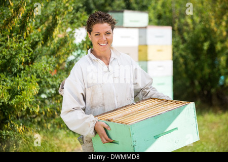 L'apiculteur femelle transportant des caisses d'abeilles Banque D'Images