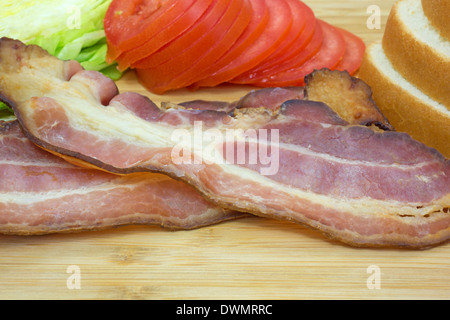 Fermer la vue de bacon cuit avec laitue tomates et le pain blanc sur une planche à découper en bois. Banque D'Images