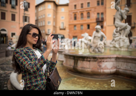 Jeune femme à prendre des photos avec un téléphone mobile, la Piazza Navona, Rome, Latium, Italie, Europe Banque D'Images