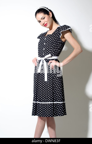 Un rétro femme habillée d'une robe d'inspiration vintage 50s, posant les mains sur sa hanche un concept moderne vintage Banque D'Images