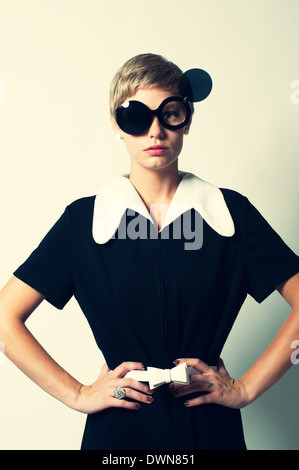 Un rétro femme posant dans un mod 60s robe, posant avec flip up lunettes rondes, les mains sur la hanche, un concept de mode vintage 60s Banque D'Images