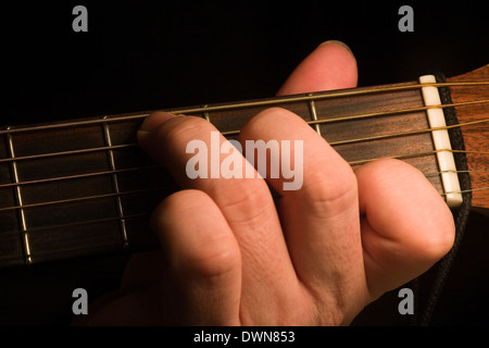 Un guitariste jouer a ut majeur première position d'ouvrir sur une guitare acoustique sur fond noir Banque D'Images