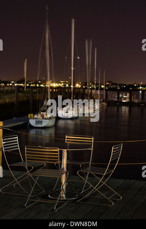 Table d'extérieur et quatre chaises le long de la Boston Loisirs Harborwalk donnant sur voiliers au quai du ventilateur Marina dans le port de Boston Banque D'Images