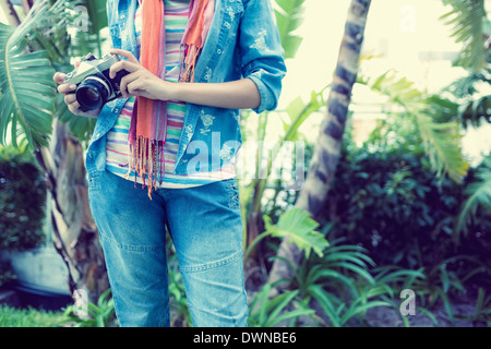 Woman wearing denim holding camera extérieur Banque D'Images
