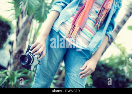 Femme portant des jeans et chemise en jean tenir l'appareil photo à l'extérieur Banque D'Images