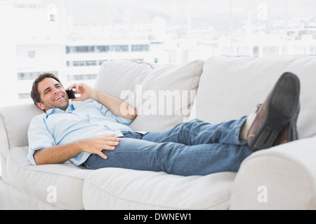 Heureux l'homme couché sur la table à parler au téléphone Banque D'Images