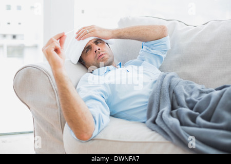 Sick man contrôler sa température sous une couverture Banque D'Images