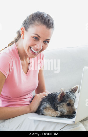 Smiling woman using laptop avec son yorkshire terrier Banque D'Images