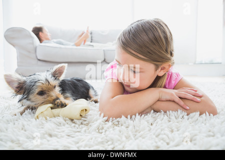 Petite fille couchée sur un tapis avec yorkshire terrier Banque D'Images