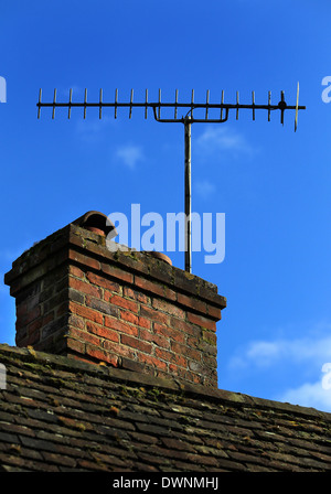 Antenne de télévision relié à une vieille cheminée en brique sur un ciel bleu sur un chalet Banque D'Images