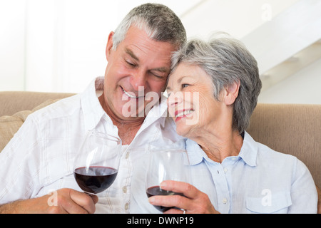 Senior couple sitting on sofa ayant des verres de vin rouge Banque D'Images