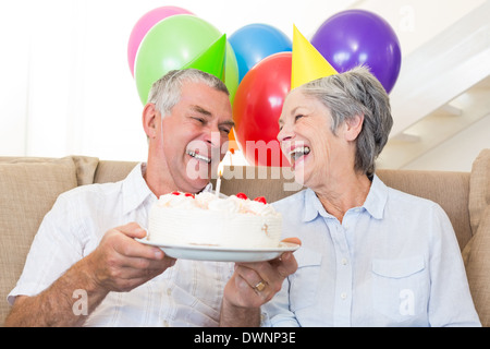 Senior couple sitting on couch fêter un anniversaire Banque D'Images