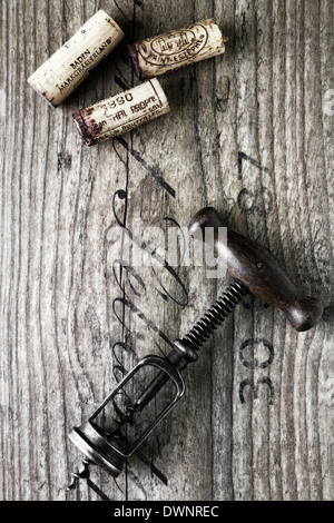 Tire-bouchon ancien avec wine corks sur une planche en bois Banque D'Images