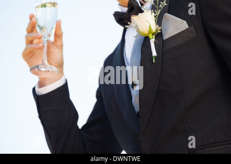 Section intermédiaire de fleurs sur le revers du mâle comme il détient le verre à champagne Banque D'Images