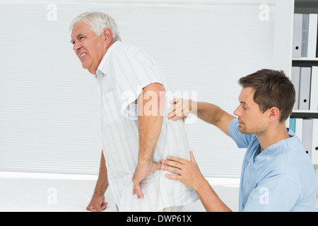 Homme physiotherapist examining senior mans retour Banque D'Images