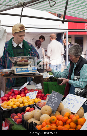 Le paiement du client pour des achats sur l'étal de fruits et légumes. Banque D'Images