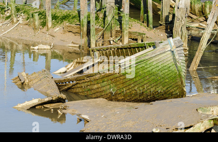 Une petite barque en bois détruite. Bateau à rames en décomposition fait de bois, coincé dans la boue. Banque D'Images