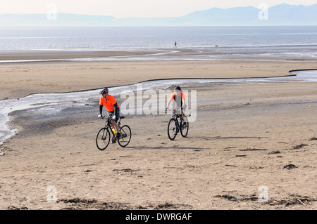 Les cyclistes sur une plage de sable fin plage près de Troon écossais dans l'Ayrshire, Ecosse, Royaume-Uni, l'Europe. Banque D'Images