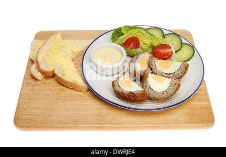 Scotch egg et de salade avec du pain et du beurre sur une planche en bois isolés contre white Banque D'Images