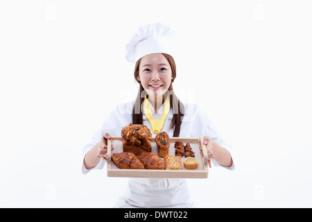 Une femme chef de pâtisserie holding a tray de pain Banque D'Images