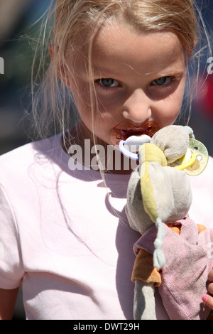 Petite fille avec une sucette et un sale toy bunny Banque D'Images